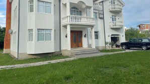 Un edificio residencial de varios pisos con una entrada central, un balcón y una chimenea.