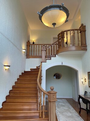 Una maestosa scala con ringhiere in legno e un lampadario, che conduce a un piano superiore.