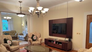Una sala de estar con un sofá, una mesa de centro, un televisor y una lámpara de araña.