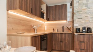 Una cucina moderna con mobili in legno, lavastoviglie integrata e pannelli posteriori in pietra.