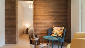 Una stanza accogliente con un muro in legno, un tavolo rotondo, una sedia blu, una sedia gialla e uno sgabello.