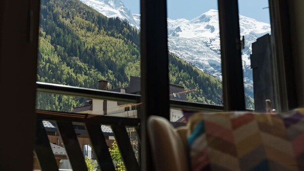 Una stanza con vista su montagne innevate e un pendio boscoso.