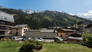 Un quartiere residenziale con edifici, auto parcheggiate e montagne sullo sfondo.