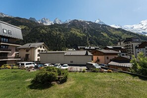 A residential area with buildings, parked cars, and a mountainous backdrop. - Sommet - Cozy | 5 guests | Central | Mont-Blanc View (Chamonix-Mont-Blanc)