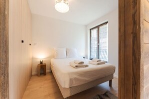 A bedroom with a bed, bedside table, and a window with curtains. - Sommet - Cozy | 5 guests | Central | Mont-Blanc View (Chamonix-Mont-Blanc)