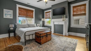 Ein Schlafzimmer mit einem Bett, einer Holzkonstruktion, einem Deckenventilator, einem Kamin und einem Fernseher an der Wand.