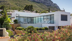 A modern building with a glass facade, a stone staircase, and a mountain backdrop. - Villa lussuosa e all'avanguardia con splendida vista (Dénia)