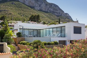 A modern building with a glass facade, a stone staircase, and a mountain backdrop.