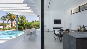 A modern interior with a pool, dining area, and living space. - Villa lussuosa e all'avanguardia con splendida vista (Dénia)