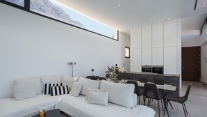 A modern living room with a sofa, coffee table, and dining area. - Villa lussuosa e all'avanguardia con splendida vista (Dénia)