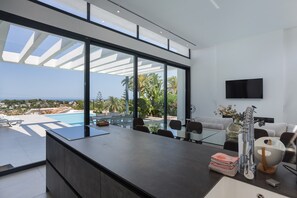 Un espace de vie moderne dotĂ© dâune grande baie vitrĂ©e, dâun tĂ©lĂ©viseur Ă Ă©cran plat et offrant une vue sur la piscine.