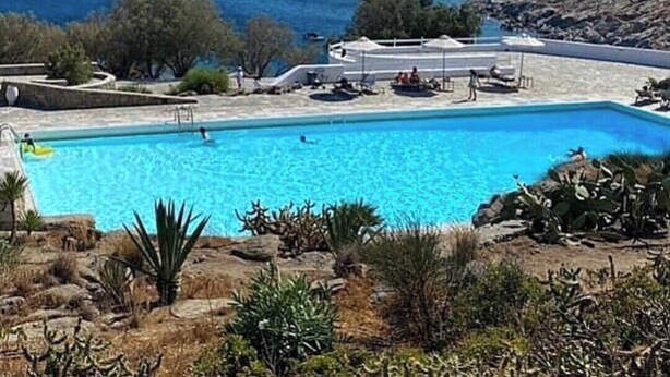 Une piscine avec vue sur la mer et un paysage vallonné.