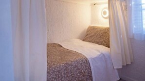 Une chambre avec un lit superposé, des rideaux, un luminaire rond et une fenêtre avec des stores.