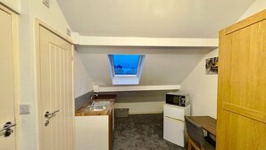 Cocina compacta con tragaluz, refrigerador, microondas y un pequeño comedor.