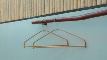 A wooden handrail with metal hooks and a metal hanger against a wall.