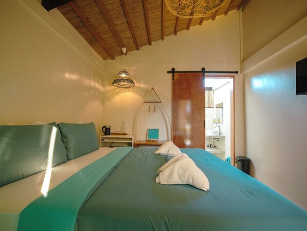 Une chambre à coucher avec un lit, un luminaire suspendu, un plafond en bois et une porte coulissante donnant sur une salle de bain.