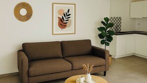 Un salon moderne comprenant un canapé, une table basse ronde, une œuvre d’art encadrée et un élément décoratif mural.