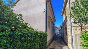 Une ruelle étroite entre deux bâtiments, avec un ciel dégagé.