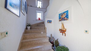 Un escalier orné de tableaux encadrés, une petite fenêtre avec une plante et une décoration représentant un voilier.