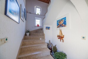 Eine Treppe mit gerahmten Bildern, ein kleines Fenster mit Pflanze und eine Segelbootdekoration.