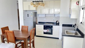 A compact kitchen with a dining table, chairs, a built-in oven, a sink, and cabinets.