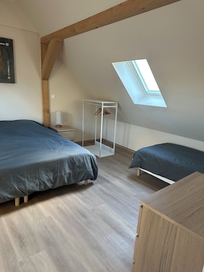 A bedroom with two beds, a skylight, a wooden ceiling beam, and a small white shelf. - Comfortable house near Europapark with large terrace (Villé)