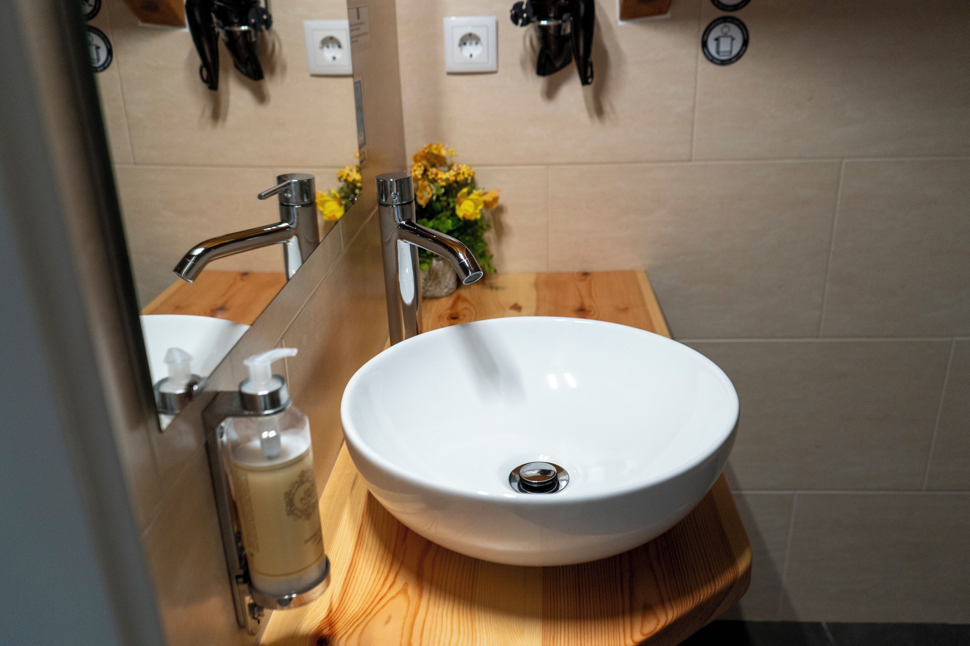 Un baño con lavamanos blanco, tocador de madera y espejo.