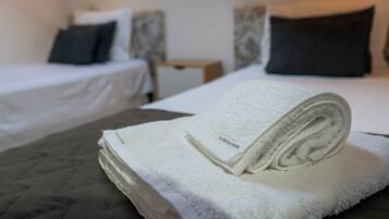 Una habitación de hotel con dos camas, una mesita de noche y una lámpara de pared.