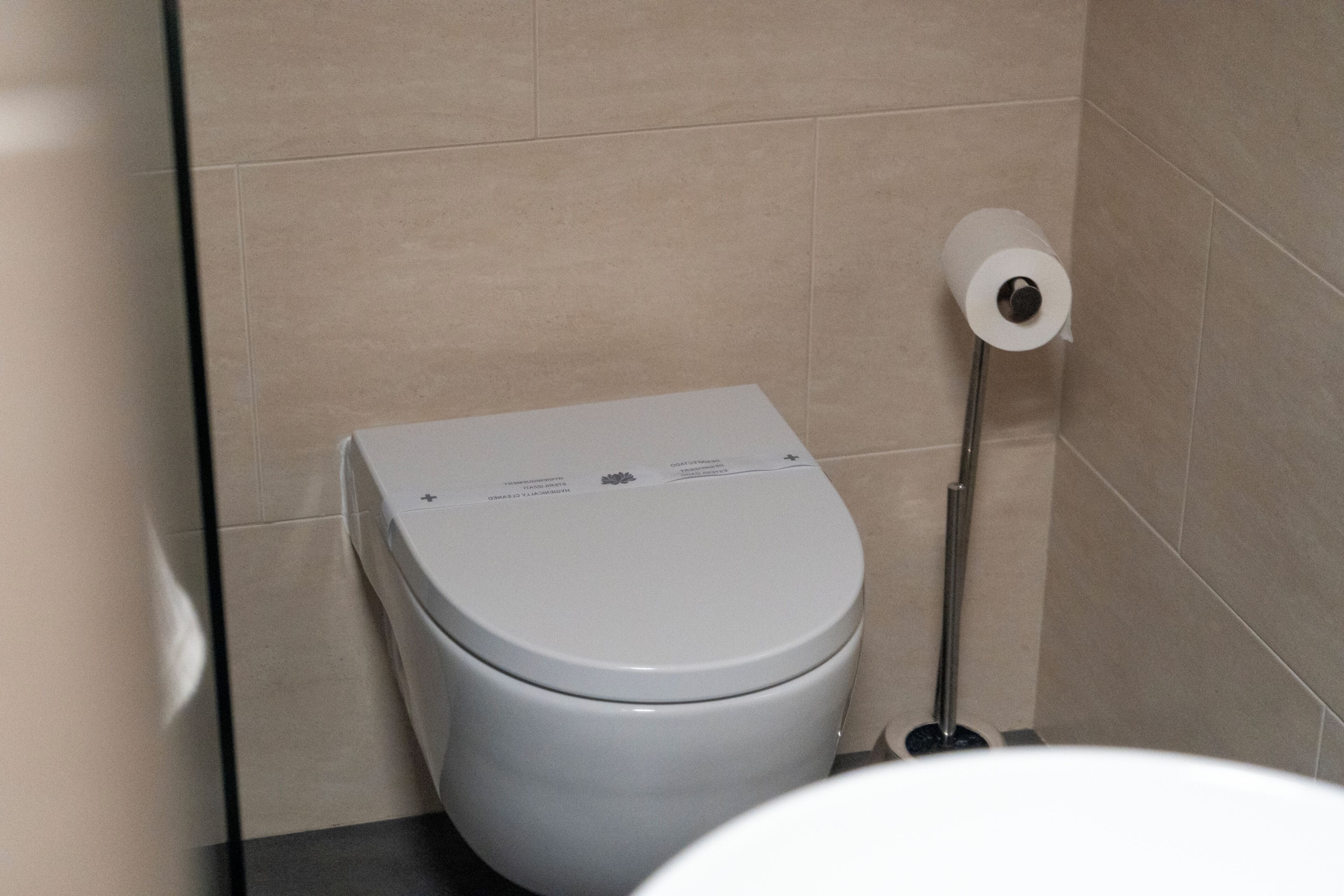 A toilet with a flush handle and a toilet paper holder.