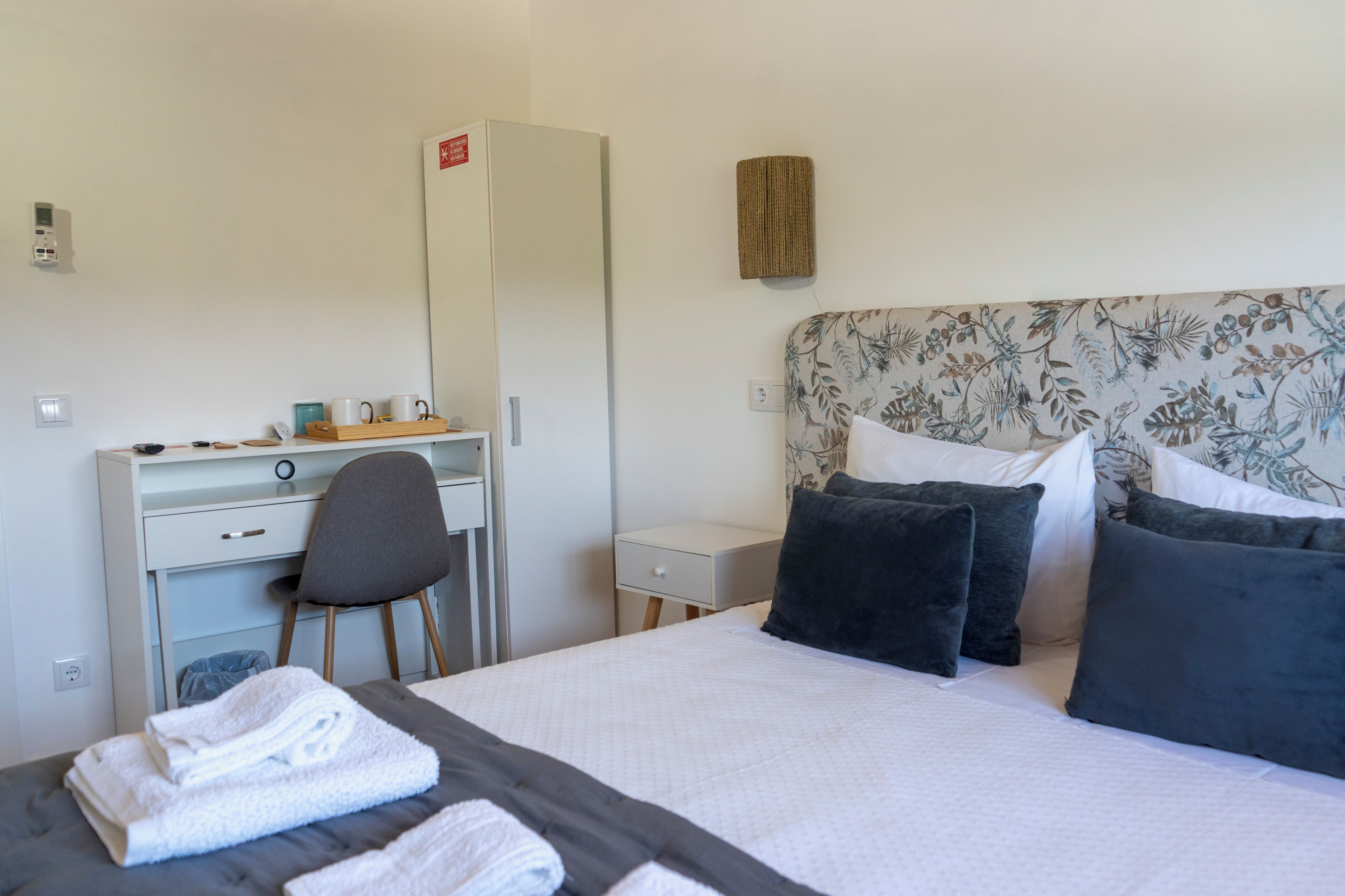 Una habitación de hotel con cama, escritorio, silla y armario.