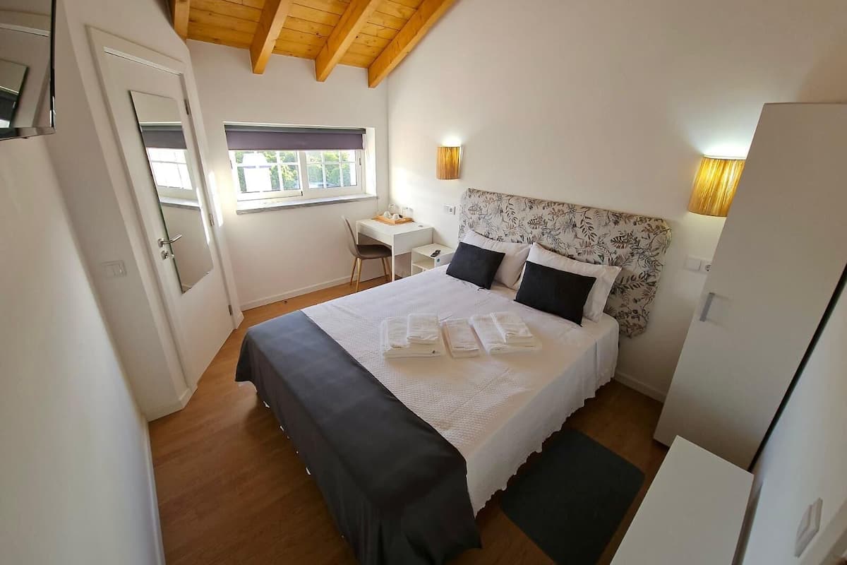 Une chambre à coucher avec un lit, des tables de chevet, un bureau et une fenêtre.