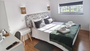 Una camera da letto con soffitto in legno, un letto con copriletto verde, una scrivania con un computer e una finestra vista verde.