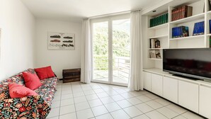 Ein Wohnzimmer mit einer Couch, einem Fernseher und einem Bücherregal.