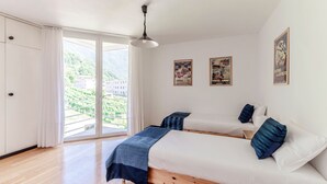 Ein Schlafzimmer mit einem Bett, zwei Kissen, einem Deckenventilator und einem Fenster mit Vorhängen.