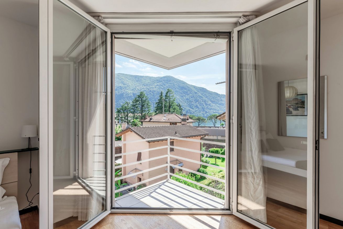 A room with a sliding glass door leading to a balcony with a mountain view.