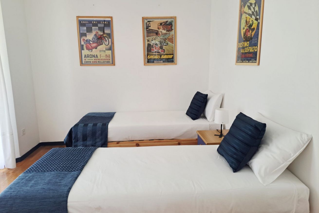 Une chambre avec deux lits, une table de chevet et trois affiches au mur.