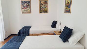 Une chambre avec deux lits, une table de chevet et trois affiches au mur.