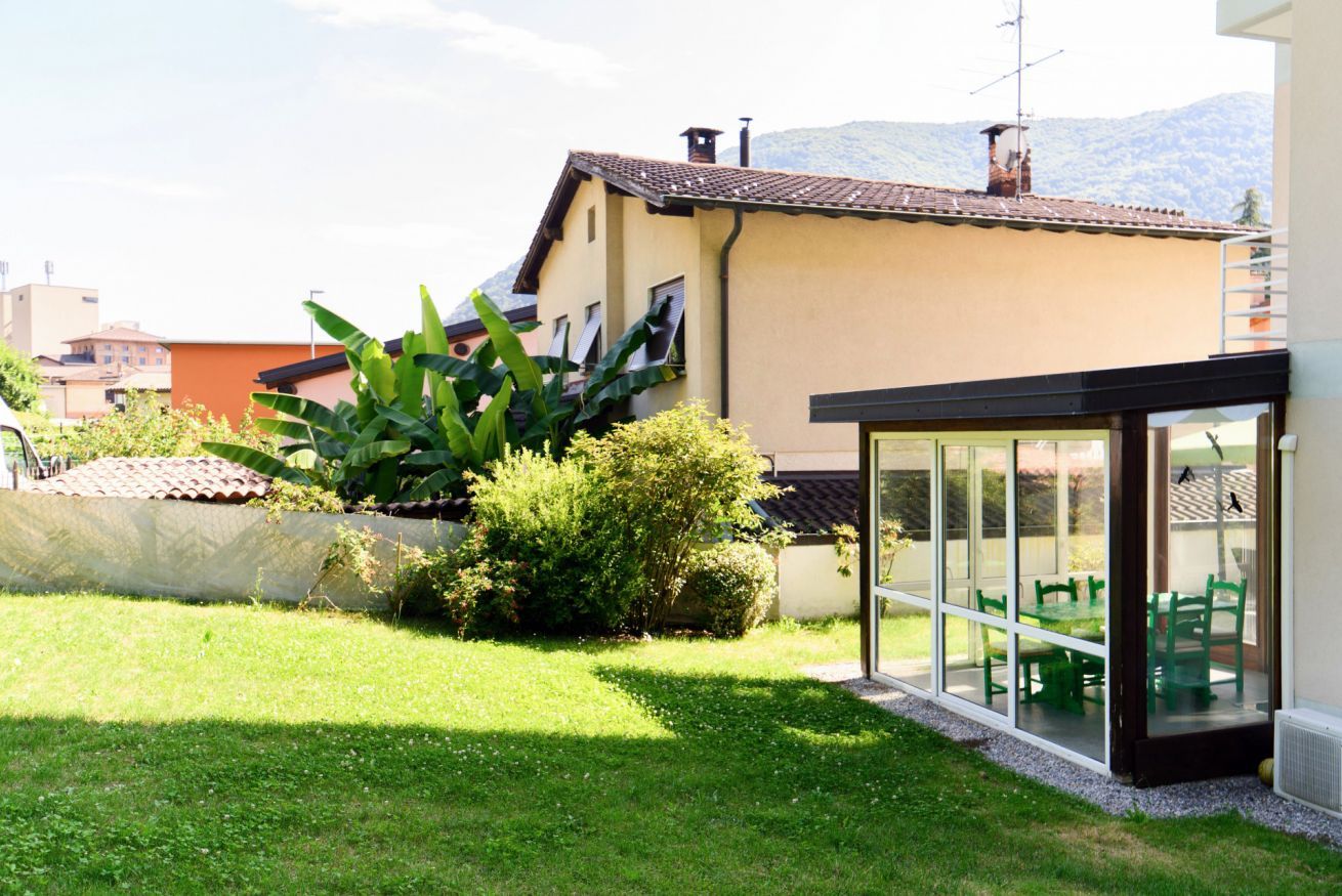 Una propiedad residencial con jardín, un patio con sillas verdes y vistas a la montaña.