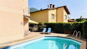 Ein Swimmingpool mit Liegestühlen und einem Rauchverbotsschild, umgeben von einem Gebäude mit Bergen im Hintergrund.