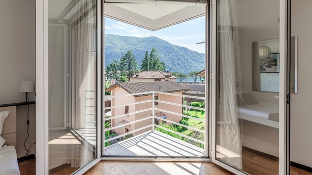 Ein Zimmer mit einer Schiebetür, die auf einen Balkon mit Bergblick führt.