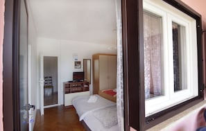 Ein Schlafzimmer mit Bett, Schreibtisch, Stuhl, Kleiderschrank und Fenster.