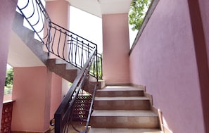 Eine Treppe mit Metallgeländer, beigen Stufen und rosafarbenen Wänden.