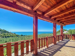 A wooden deck with a view of the sea and green hills.
