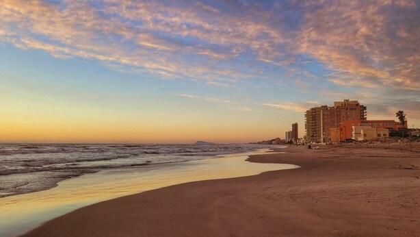 A beach with a clear sky, waves, and buildings in the background. - Apartment 'Playa Valencia' with Terrace, Wi-Fi and Air Conditioning (Mareny de Barraquetes)