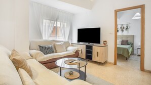 A modern living room with a sofa, a coffee table, a TV, and a wooden cabinet. - Apartment 'Playa Valencia' with Terrace, Wi-Fi and Air Conditioning (Mareny de Barraquetes)
