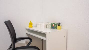 A white desk with a calendar, a yellow figurine, and a small plant.