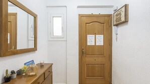 A hallway with a wooden door, a small window, a mirror, and a welcome sign. - Apartment 'Playa Valencia' with Terrace, Wi-Fi and Air Conditioning (Mareny de Barraquetes)