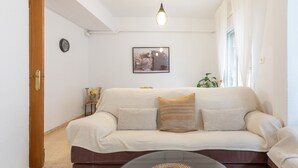 A living room with a sofa, a glass coffee table, a wall-mounted picture, and a door. - Apartment 'Playa Valencia' with Terrace, Wi-Fi and Air Conditioning (Mareny de Barraquetes)