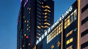 A hotel with a modern facade, large windows, and illuminated signage. - Immersing Hotel (Chengdu)