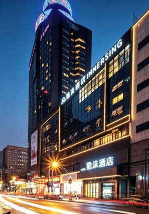 Un hotel con fachada moderna, amplias ventanas y señalización iluminada.